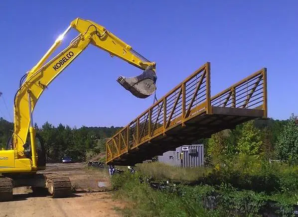 A crane is lifting a bridge over the road.