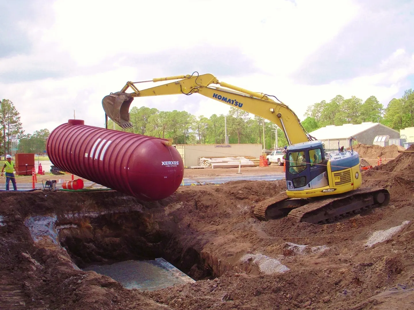 A large red tank is being used to fill up the hole.