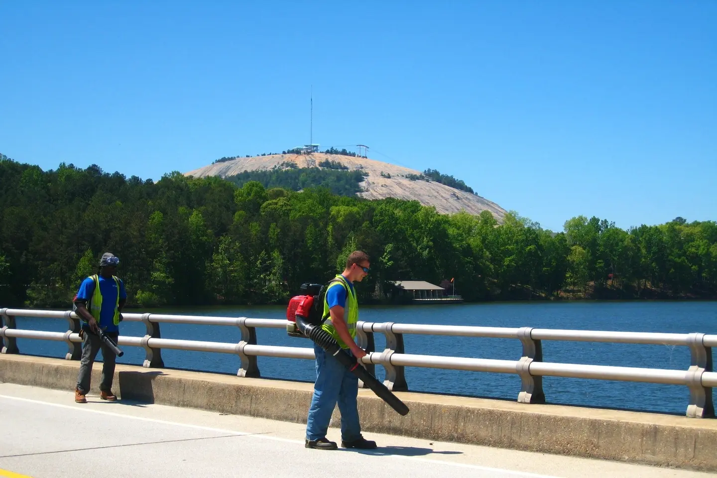 A man standing on the side of a road near water.