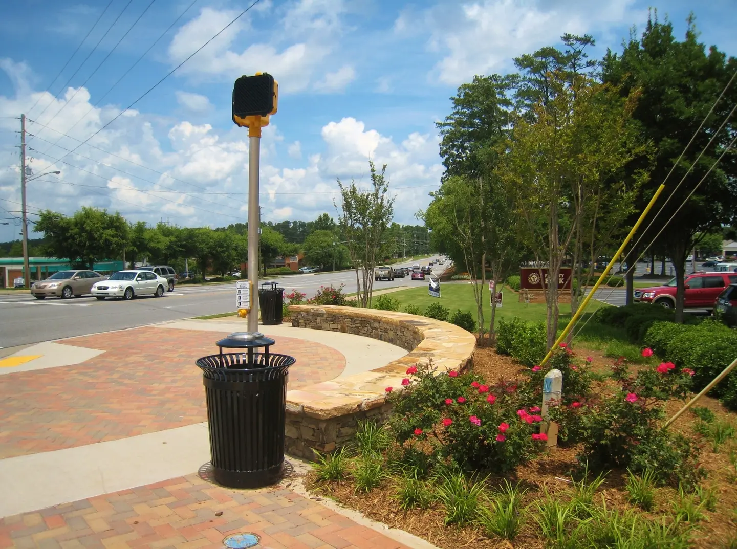 A black trash can sitting on the side of a road.