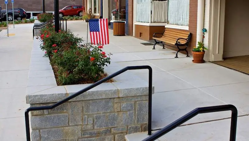 A bench and some flowers on the side of a building.