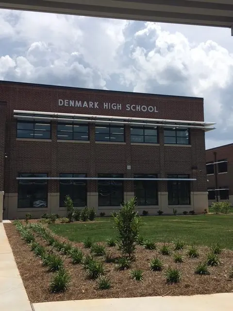 A large brick building with grass growing in front of it.