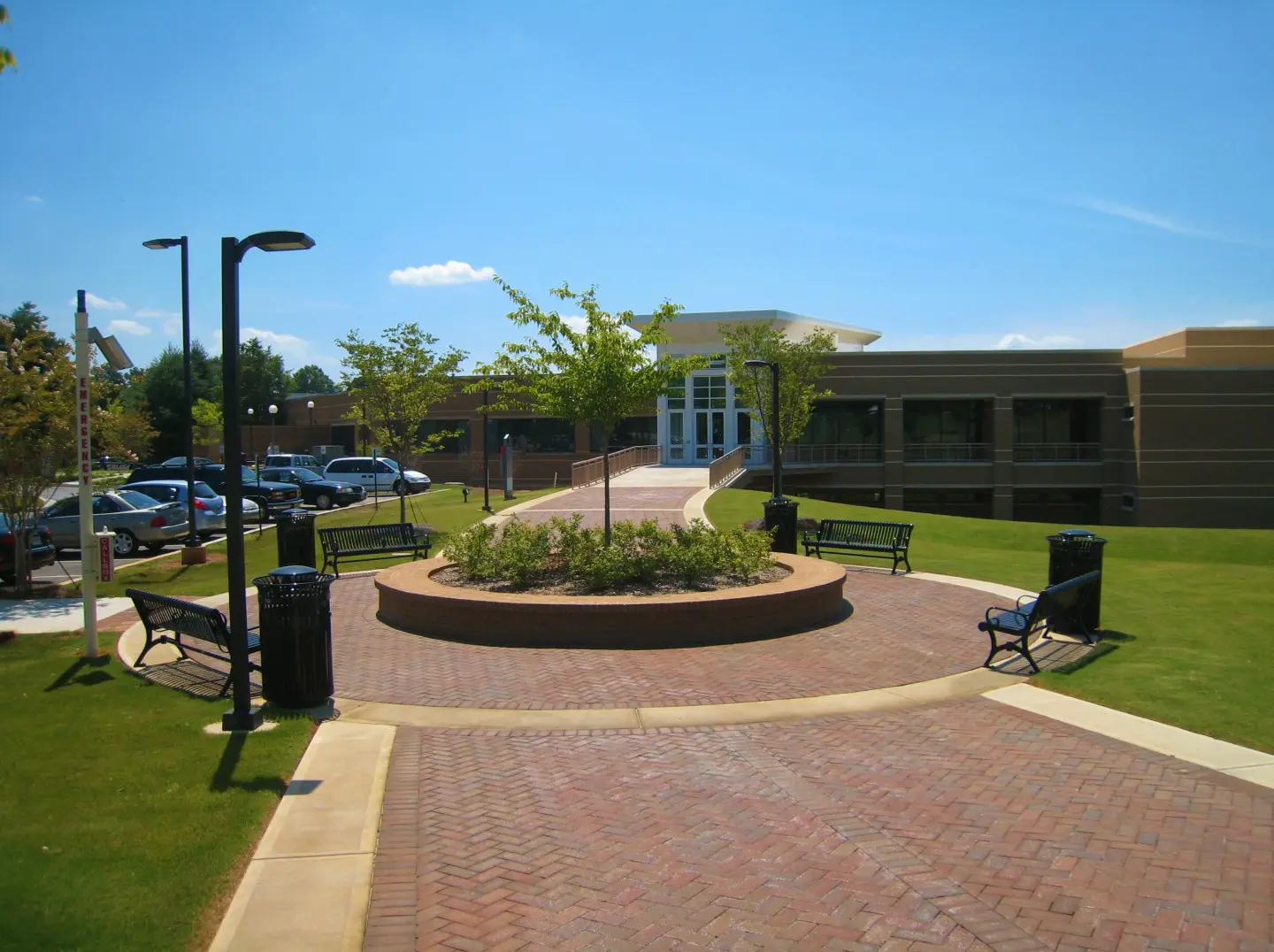 A brick walkway with benches and trees in the background.