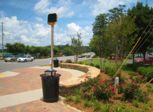 A black trash can sitting on the side of a road.