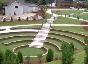 A circular garden with steps and benches in the middle.