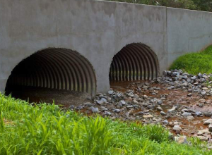 A couple of large concrete pipes on the side of a river.