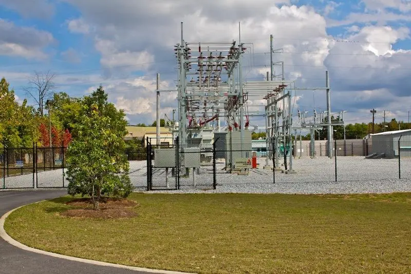 A power plant with many wires on the side of it.